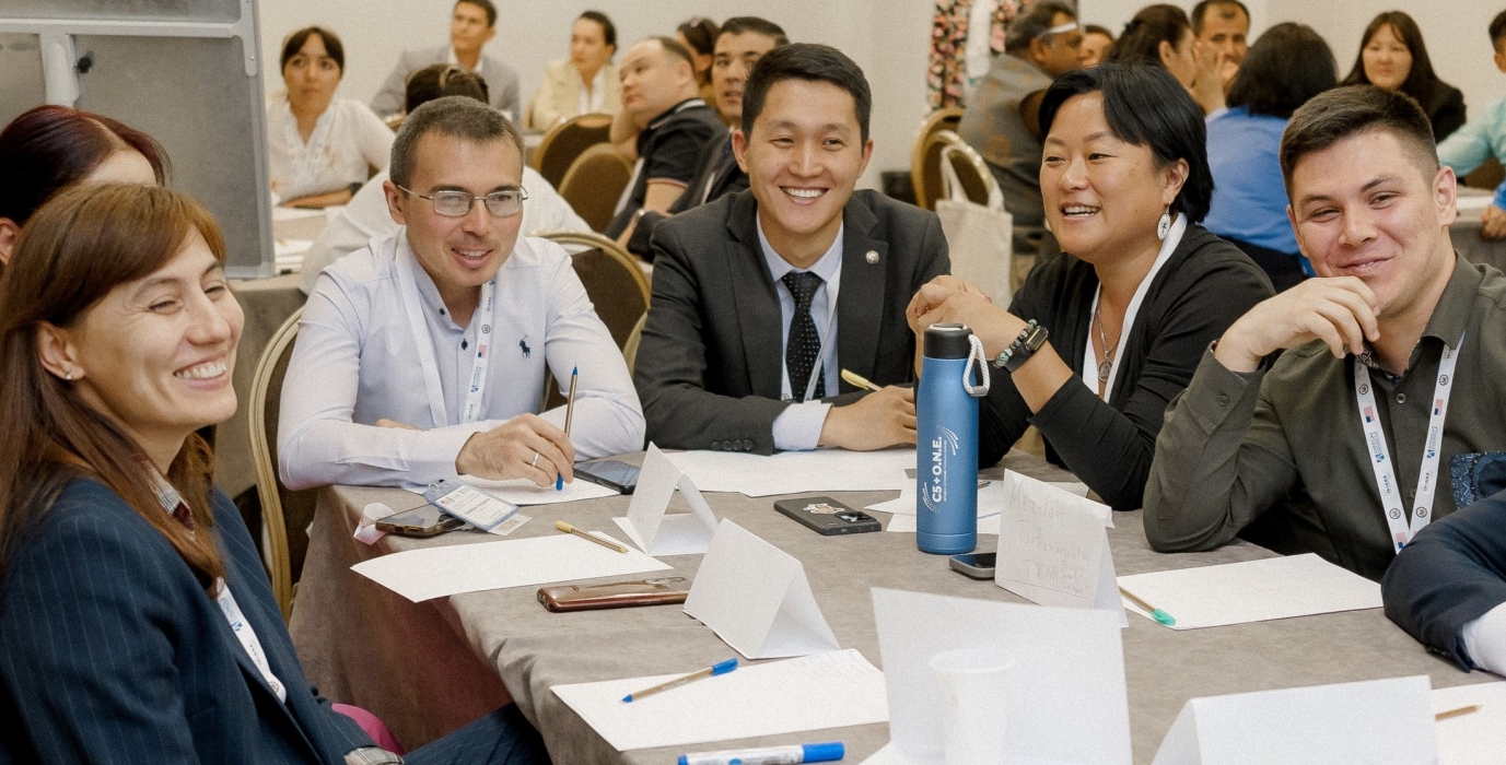 C5+O.N.E. Program Participants Smiling at Conference Brainstorm Session