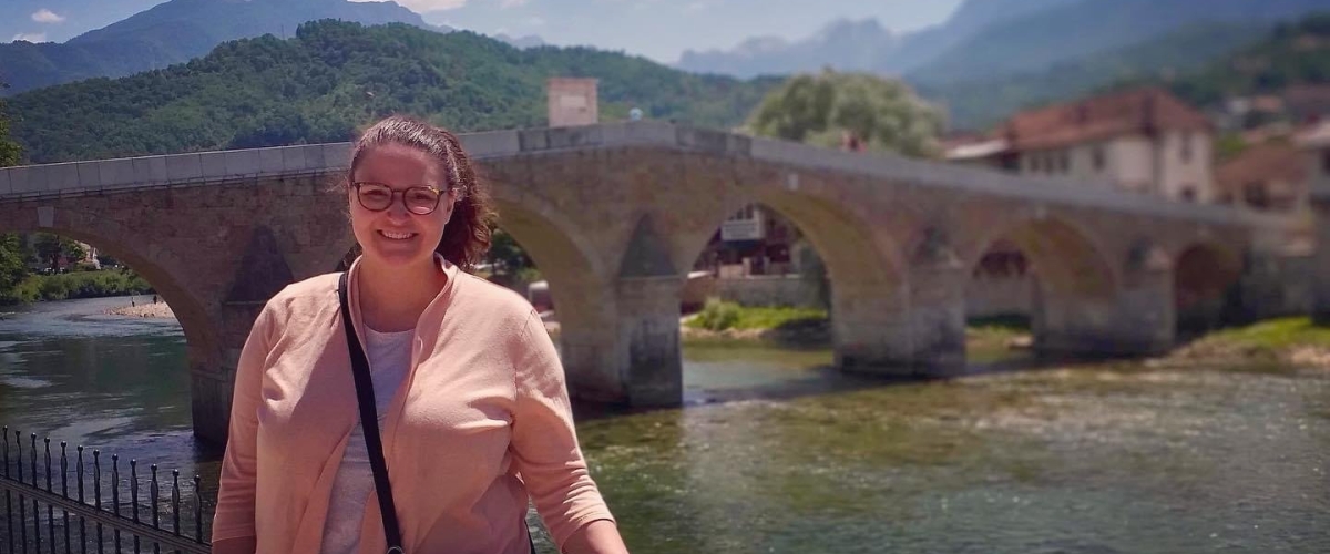 Study abroad participant posing in front of a bridge in a distant city 